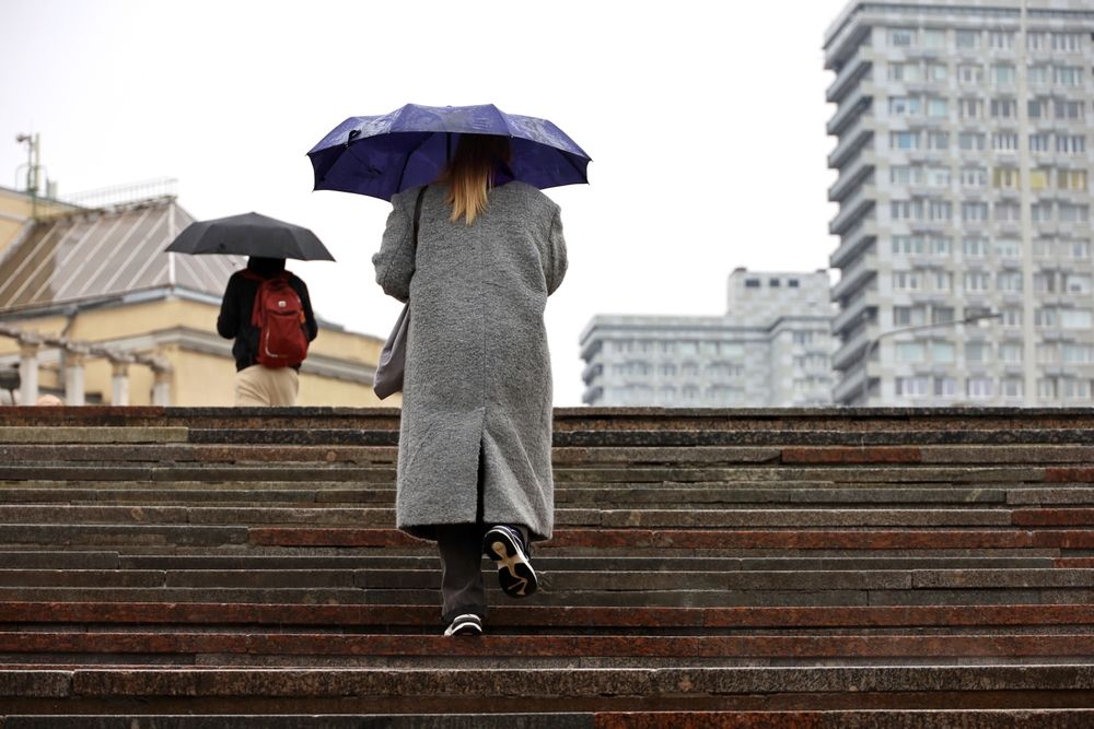 Woman,With,Umbrella,Walking,Up,The,Steps,On,City,Buildings