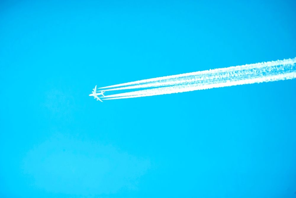 repülés,An,Airplane,With,Four,Clear,Lines,Of,Contrails,Against,A