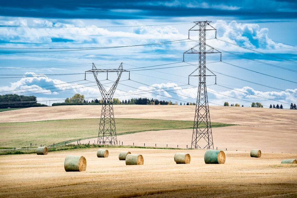 Transmission,Towers,And,Power,Lines,Overlooking,A,Farm,Field,During