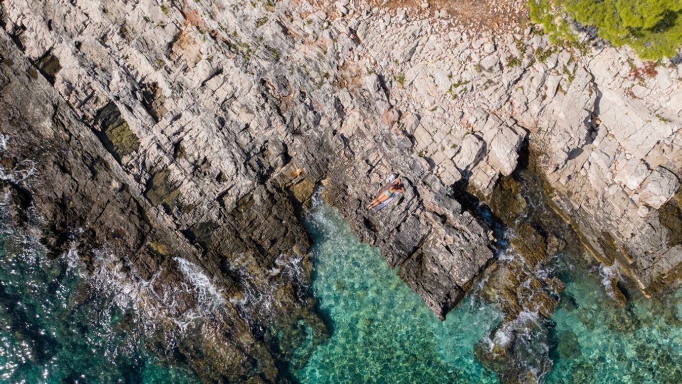 Aerial,,Top,Down:,Unrecognizable,Female,Tourist,Sunbathes,On,The,Rocky