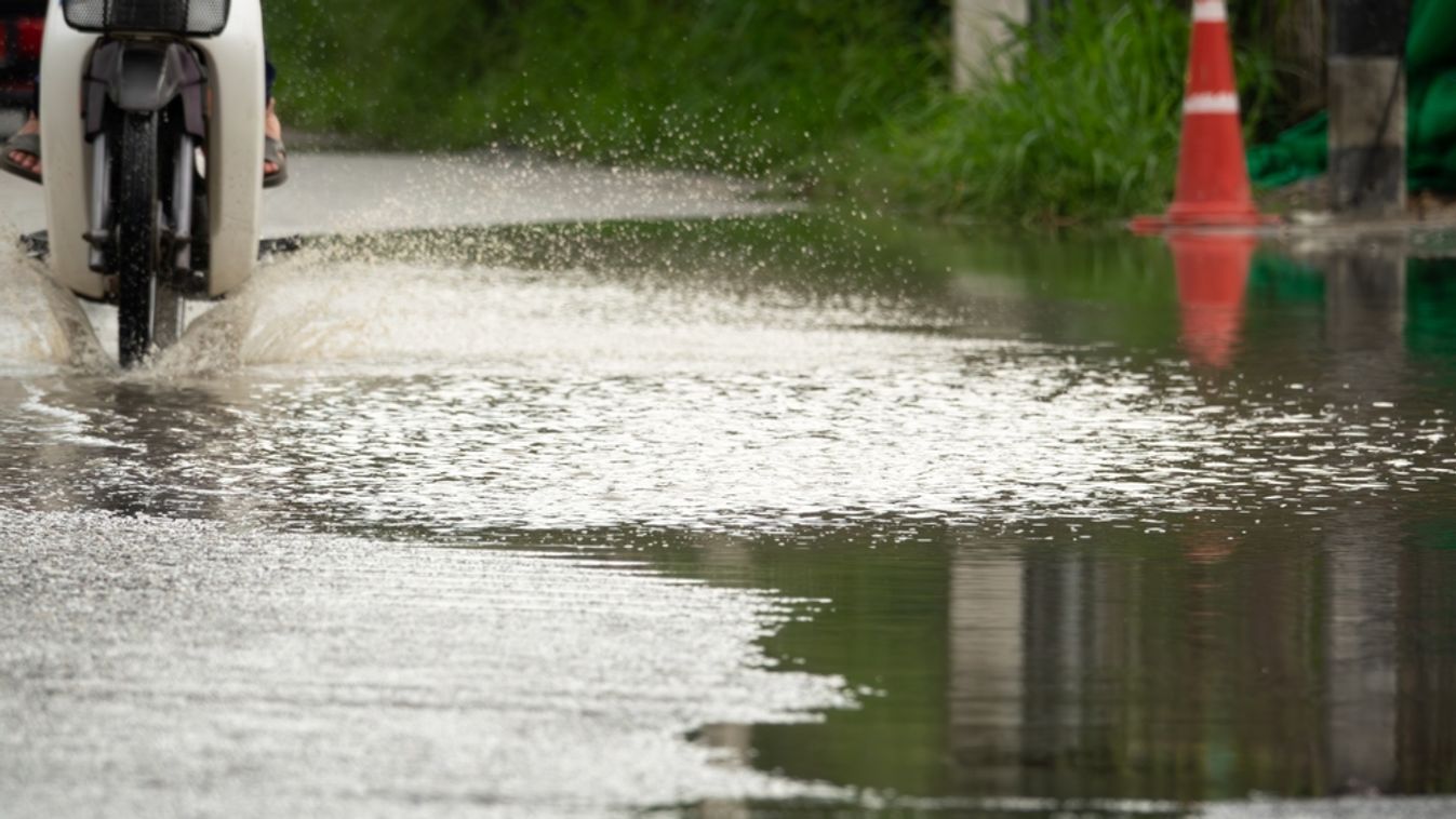 A,Motorcycle,Is,Driving,Through,A,Flooded,Street.,The,Water