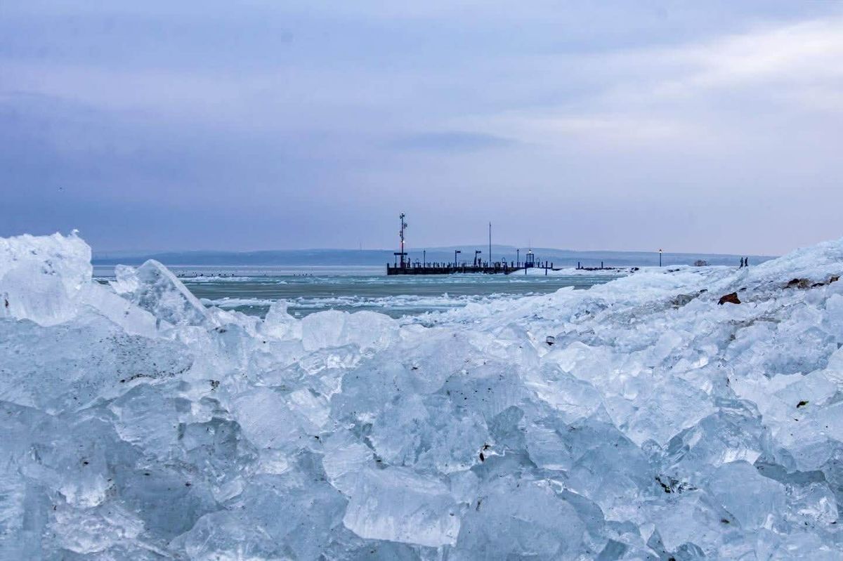 partra sodródott jég a Balatonon, háttérben a tóval és stéggel